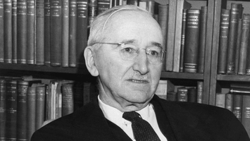 A photograph of F. A. Hayek in front of a bookshelf at the University of Chicago.