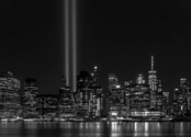 A black and white photo of the NY skyline, with bright lights in place of the World Trade Center's twin towers. 