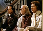 William Daniels as John Adams, Howard De Silva as Benjamin Franklin, and Ken Howard as Thomas Jefferson sit side by side on a staircase, singing.
