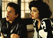 Joe Pesci holds his mouth open while speaking and Marissa Tomei sits next to him.