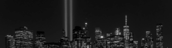 A black and white photo of the NY skyline, with bright lights in place of the World Trade Center's twin towers. 