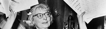Jane Jacobs holds up handfuls of documents.
