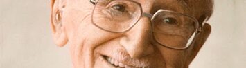 A photographic portrait of a smiling, elderly F.A. Hayek.